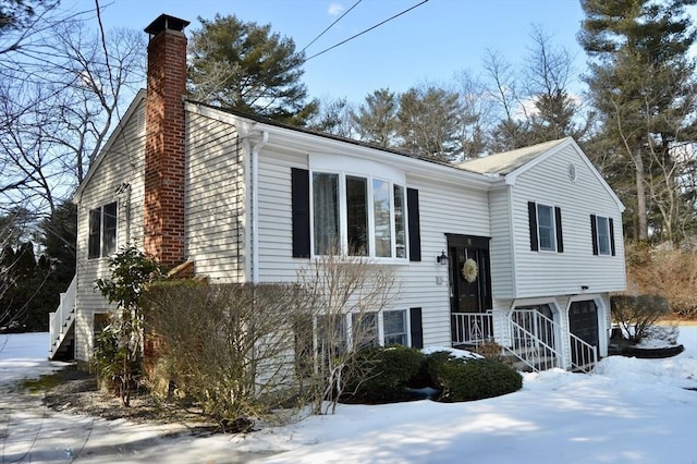 raised ranch featuring a chimney and an attached garage