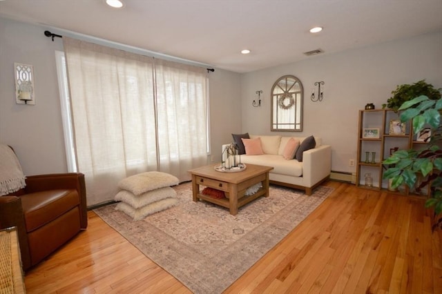 living room featuring visible vents, a baseboard heating unit, wood finished floors, and recessed lighting