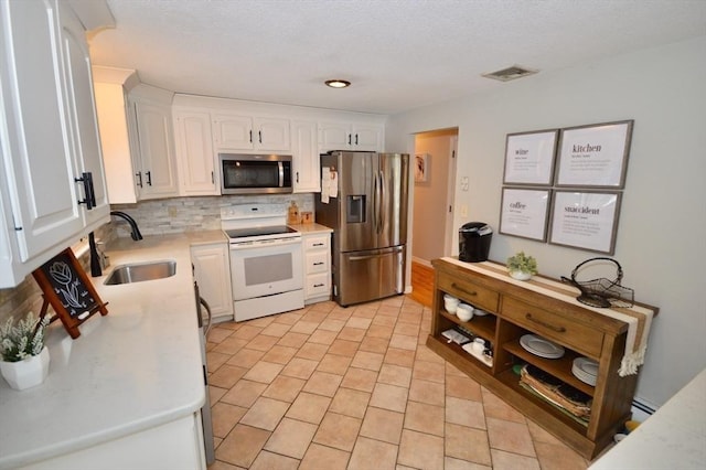 kitchen with stainless steel appliances, light countertops, visible vents, white cabinetry, and a sink