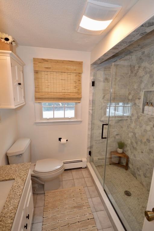 bathroom featuring a baseboard radiator, a shower stall, toilet, and tile patterned floors