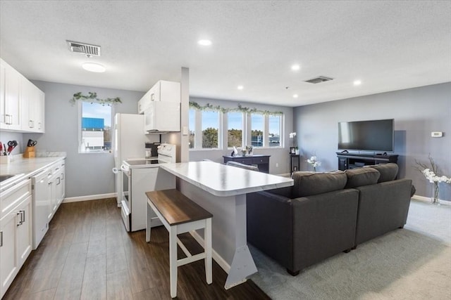 kitchen featuring white appliances, a peninsula, visible vents, and a healthy amount of sunlight