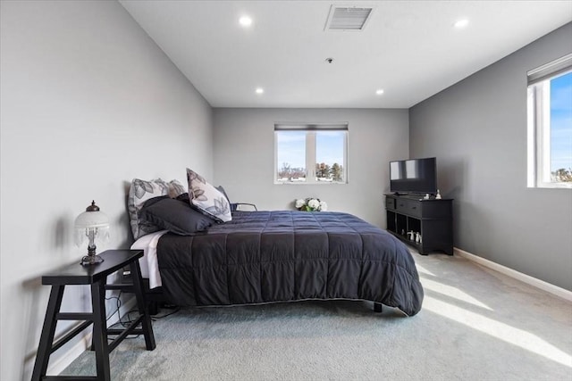 bedroom with visible vents, light carpet, multiple windows, and baseboards