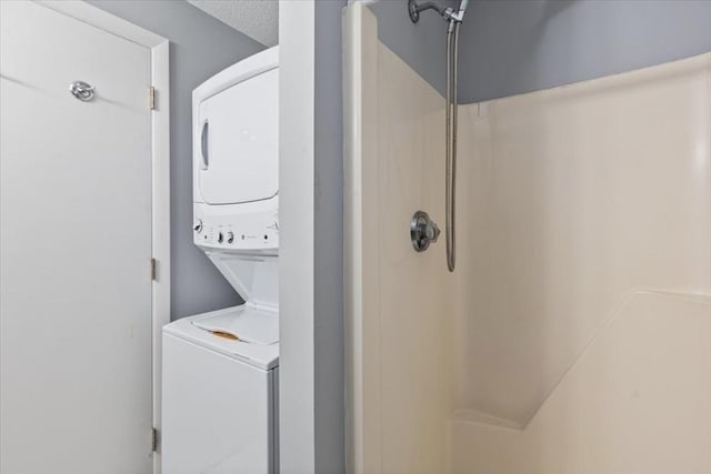 clothes washing area featuring laundry area, a textured ceiling, and stacked washing maching and dryer