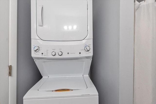 clothes washing area featuring stacked washer and dryer and laundry area