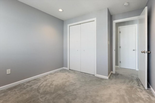 unfurnished bedroom featuring baseboards, carpet floors, and a closet