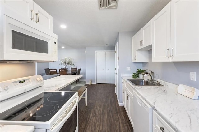 kitchen with visible vents, a sink, white cabinets, white appliances, and dark wood-style flooring