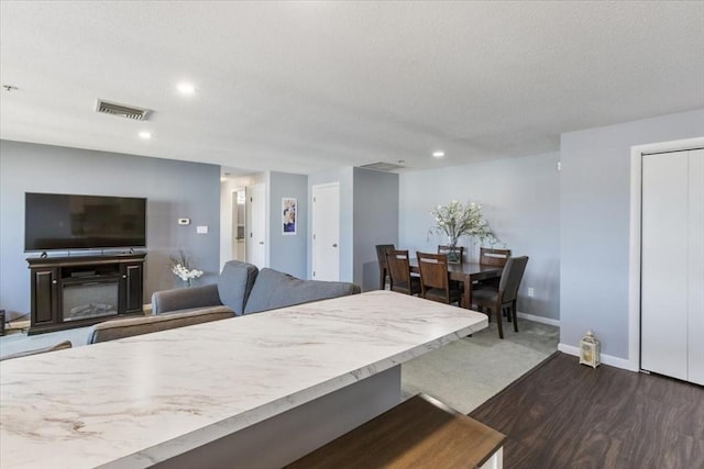 dining area with baseboards, visible vents, dark wood-style flooring, and a textured ceiling