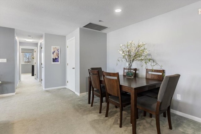 carpeted dining space featuring baseboards, visible vents, and a textured ceiling