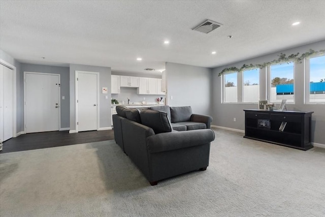 carpeted living room featuring recessed lighting, baseboards, visible vents, and a textured ceiling