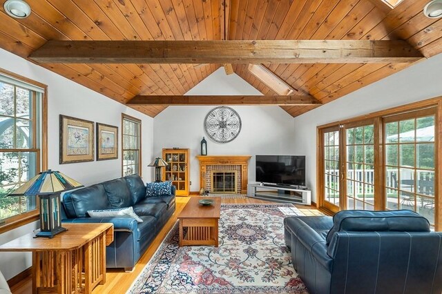 living area featuring light wood finished floors, wooden ceiling, plenty of natural light, and a brick fireplace