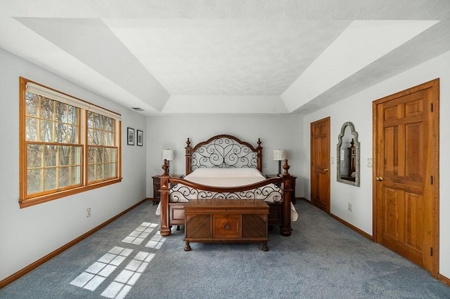 bedroom with carpet flooring, a tray ceiling, and baseboards