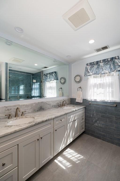 full bathroom with tile walls, double vanity, tile patterned floors, and a shower