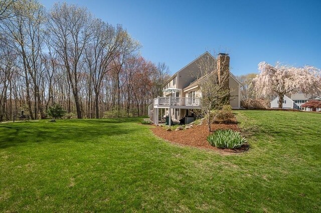 view of side of home with a chimney, a wooden deck, and a yard
