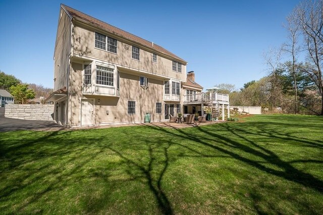 rear view of property with a deck, a yard, and stairway