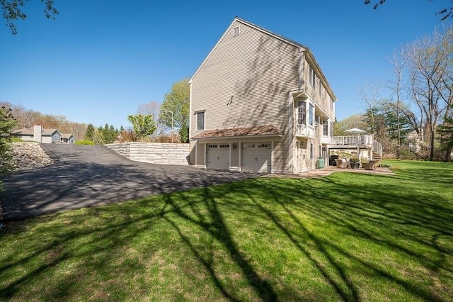 rear view of house featuring stairway, an attached garage, a wooden deck, and a lawn