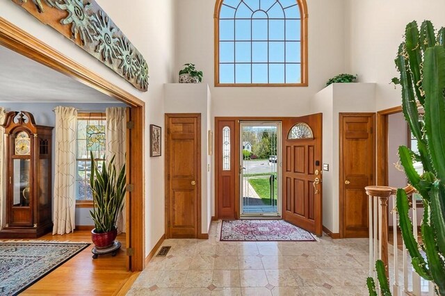 foyer entrance with baseboards and a towering ceiling