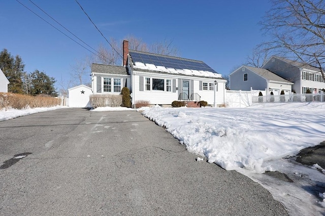 view of front of property featuring a chimney, fence, and solar panels