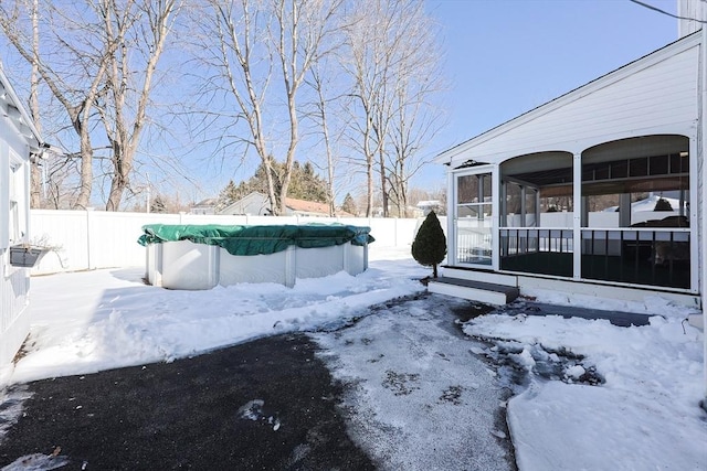 yard layered in snow with a fenced in pool, a sunroom, and a fenced backyard