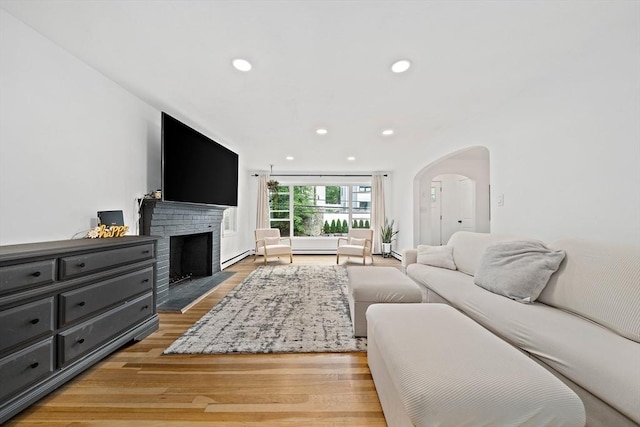 359 Corey St, Boston, MA 02132 - living room with light wood finished floors, recessed lighting, arched walkways, a fireplace, and a baseboard heating unit