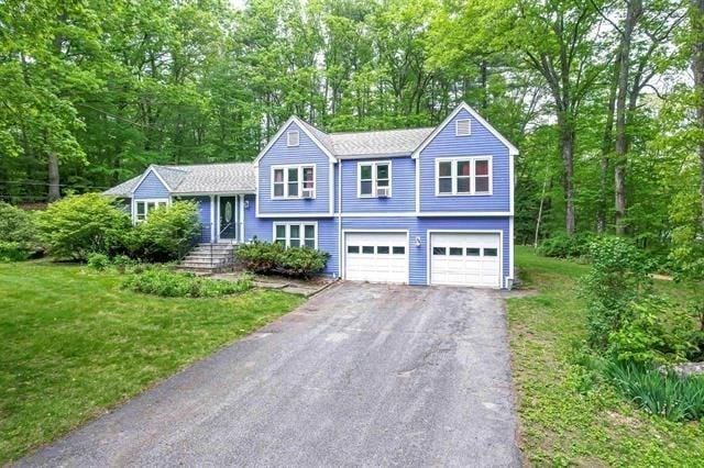 5 Plouff Ln, Exeter, NH 03833 - tri-level home featuring driveway, an attached garage, a front lawn, and view of wooded area