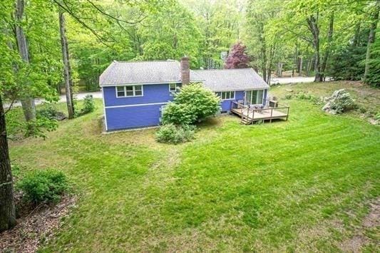 5 Plouff Ln, Exeter, NH 03833 - back of house featuring a view of trees, a wooden deck, a yard, and a chimney