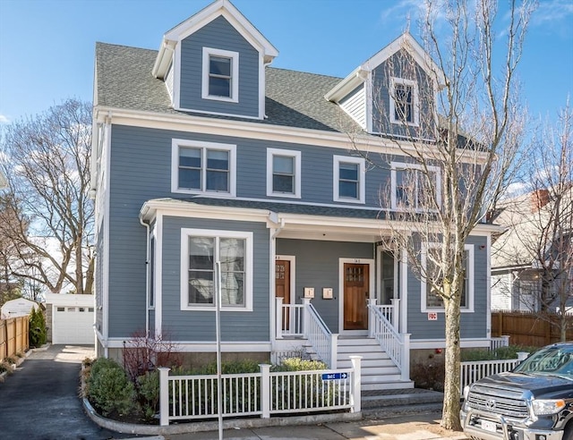 view of front of house with a fenced front yard, a porch, an outdoor structure, and a shingled roof