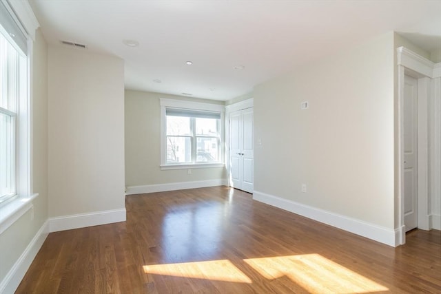 unfurnished room with visible vents, baseboards, and wood finished floors