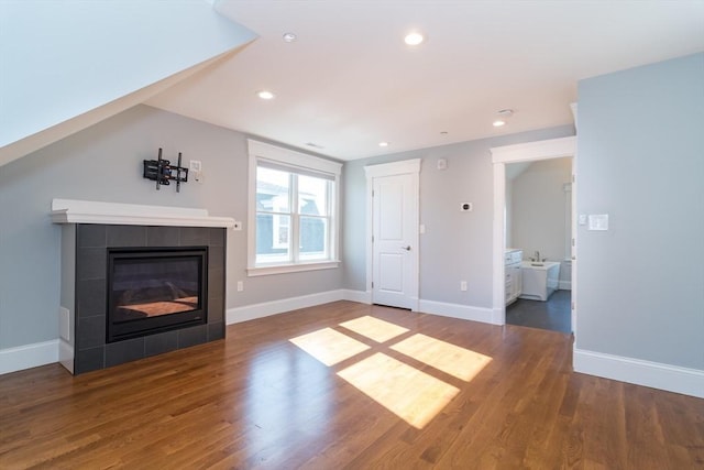 unfurnished living room with wood finished floors, recessed lighting, a fireplace, and baseboards