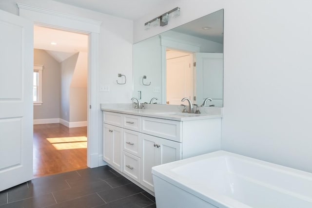 bathroom featuring a sink, a tub, wood finished floors, double vanity, and vaulted ceiling