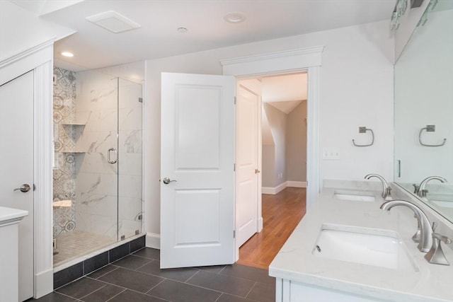 bathroom featuring a sink, double vanity, a shower stall, and tile patterned floors