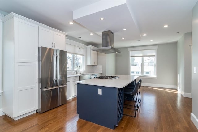 kitchen featuring a center island, appliances with stainless steel finishes, island exhaust hood, white cabinets, and a sink