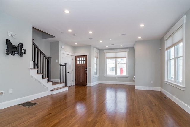 foyer featuring visible vents, stairway, baseboards, and wood finished floors