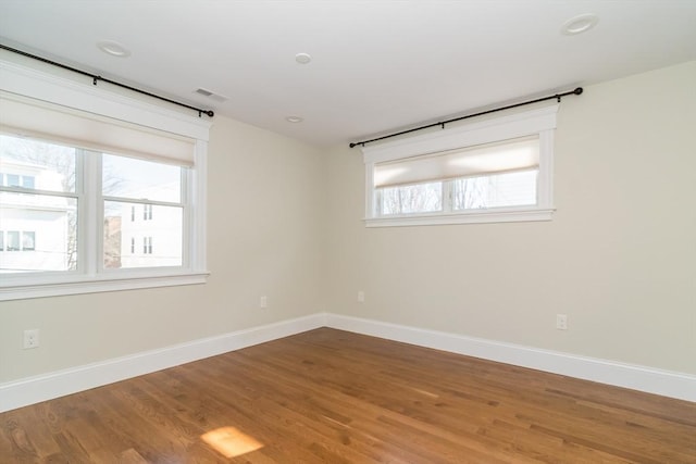 empty room featuring wood finished floors, baseboards, and visible vents