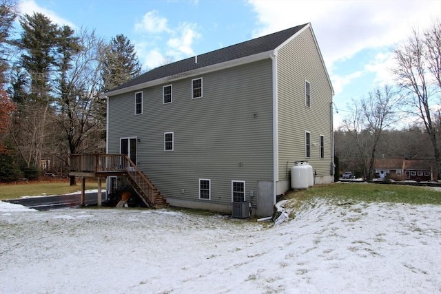 snow covered house with cooling unit and a deck