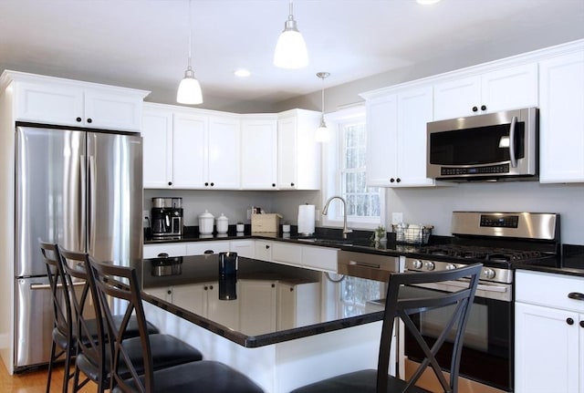 kitchen featuring sink, a breakfast bar, white cabinetry, stainless steel appliances, and decorative light fixtures