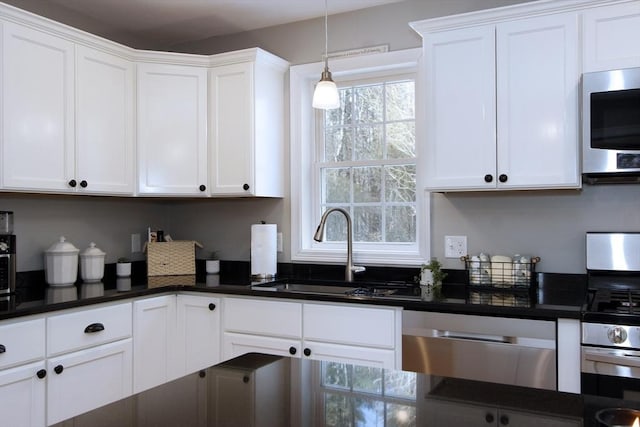 kitchen with hanging light fixtures, appliances with stainless steel finishes, sink, and white cabinets