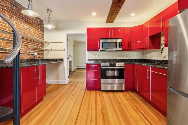 kitchen featuring light wood-type flooring, appliances with stainless steel finishes, dark stone counters, and brick wall