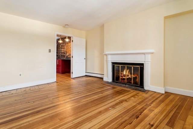 unfurnished living room featuring a baseboard heating unit and hardwood / wood-style floors