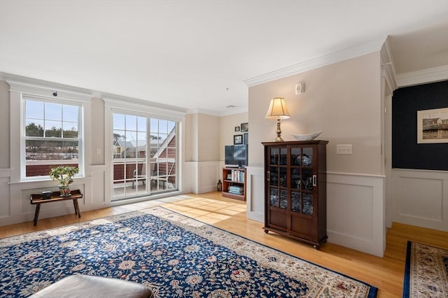 interior space featuring wood finished floors, crown molding, and wainscoting