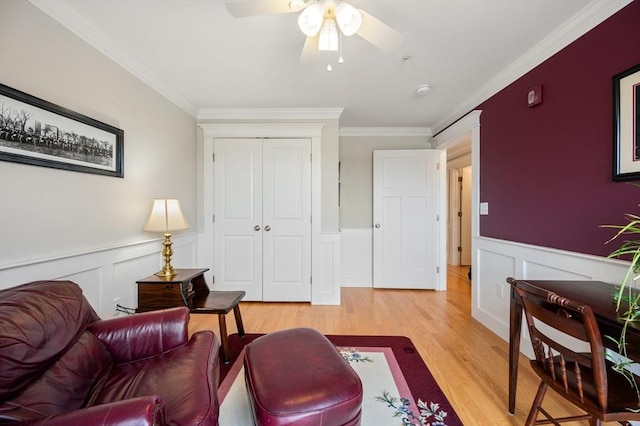 living room with a wainscoted wall, light wood-style flooring, and ornamental molding