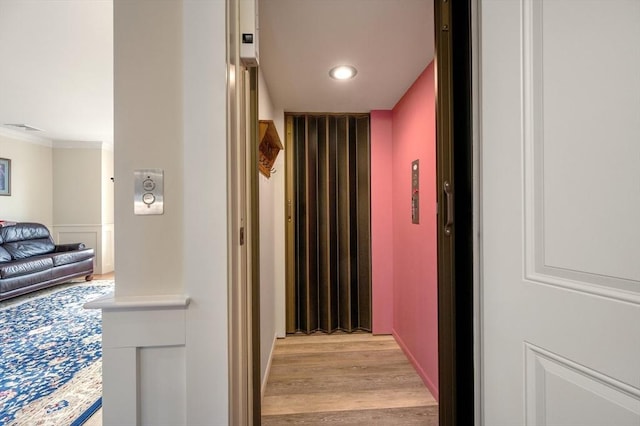 hall featuring ornamental molding, light wood-type flooring, elevator, and recessed lighting