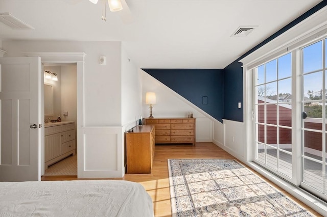 bedroom featuring a wainscoted wall, a ceiling fan, visible vents, and wood finished floors