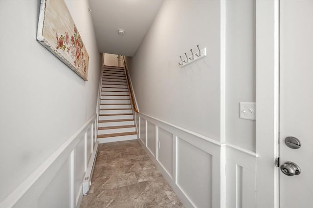 stairs featuring a wainscoted wall and a decorative wall