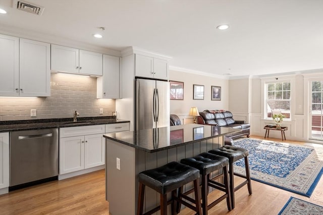 kitchen featuring crown molding, visible vents, appliances with stainless steel finishes, a sink, and a kitchen breakfast bar