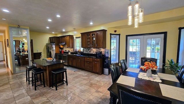 kitchen featuring a center island, sink, decorative backsplash, decorative light fixtures, and stainless steel fridge