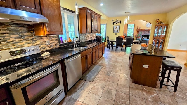 kitchen featuring a center island with sink, appliances with stainless steel finishes, plenty of natural light, and tasteful backsplash