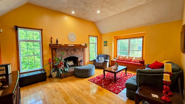 living room with a healthy amount of sunlight, wood-type flooring, a fireplace, and lofted ceiling