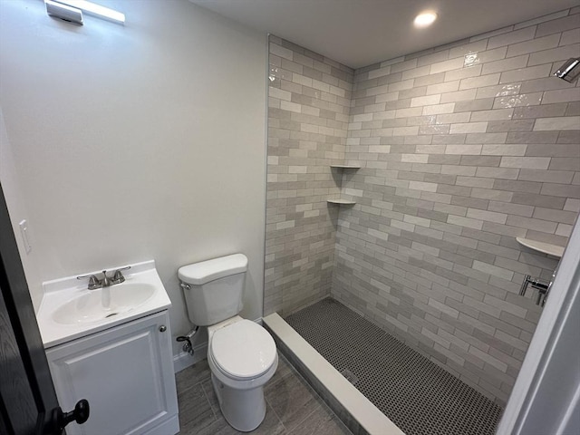 bathroom with vanity, a tile shower, and toilet