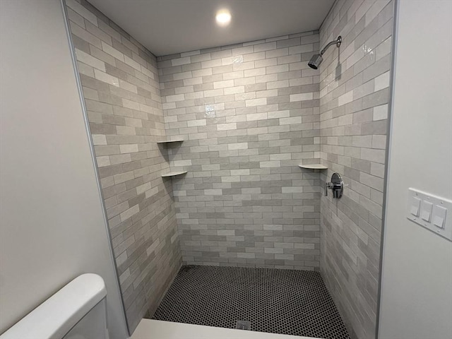 bathroom featuring tiled shower and toilet