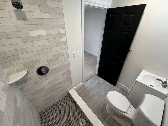 bathroom featuring vanity, toilet, and tiled shower